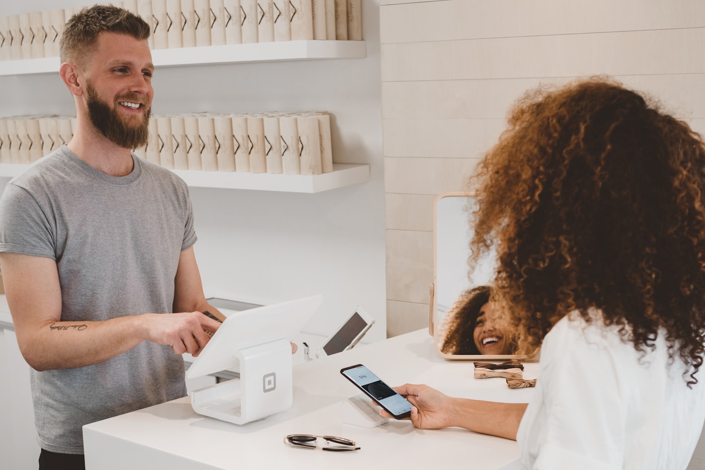 Comerciante atiende a una clienta que paga con su teléfono en el punto de venta de un local.